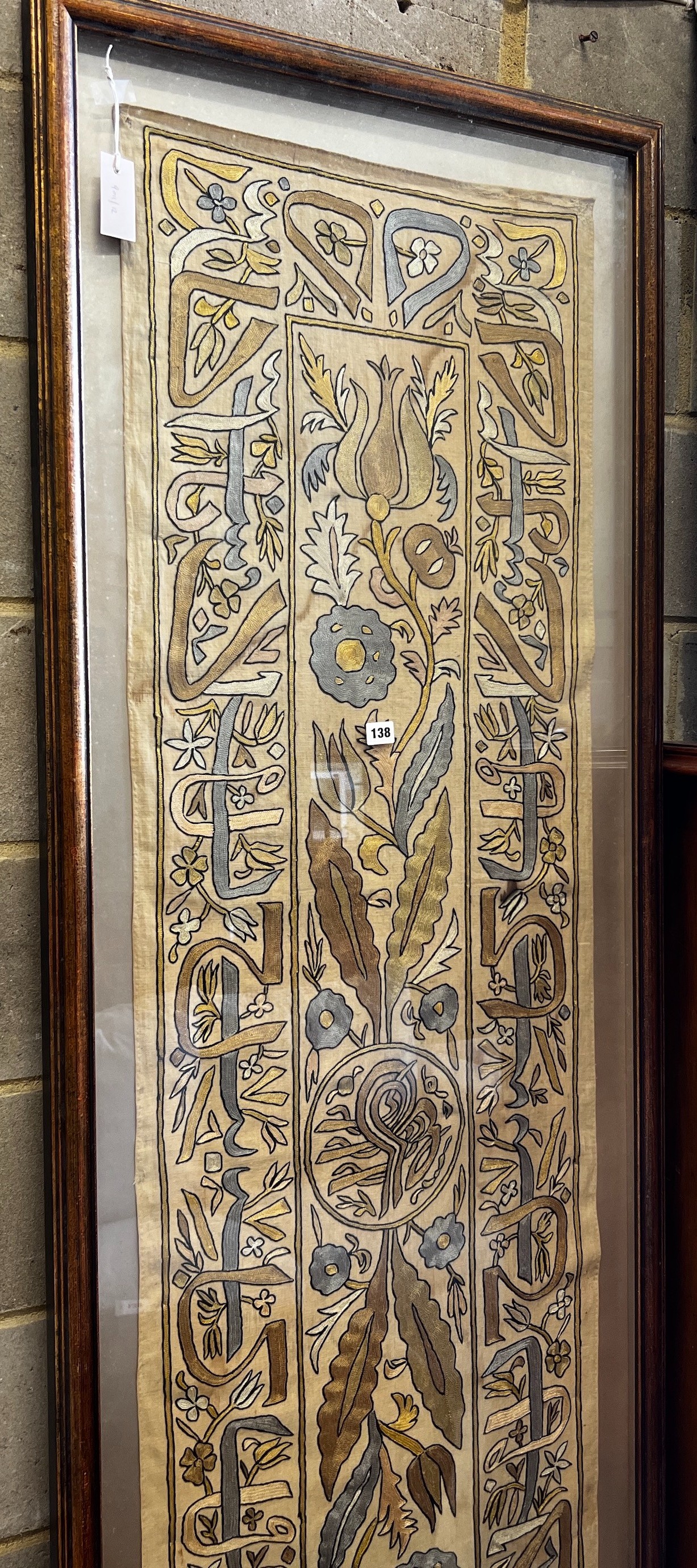 A polychrome embroidered panel, framed, the panel width 51cm, height 192cm